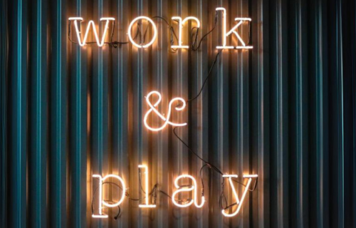 leuchtender Schriftzug "work & play" in einzelnen Buchstaben vor einer dunkelblauen Wellblechwand
